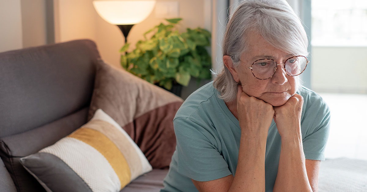 concerned elderly woman sitting on couch