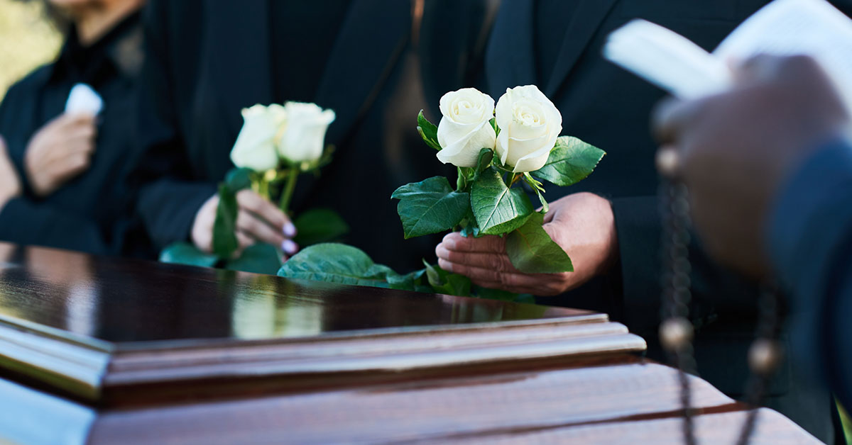 people placing flowers on casket