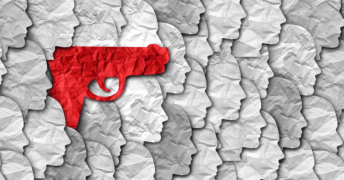 red pistol amongst paper silhouettes of peoples heads