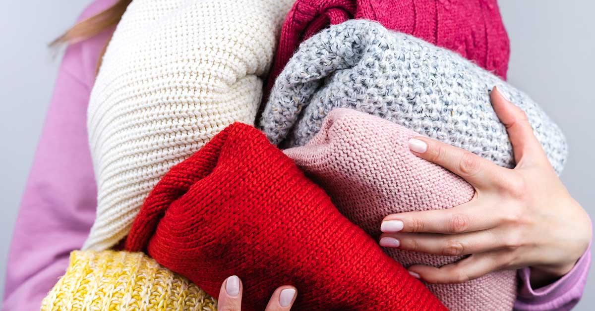 person holding various towels and blankets. Declutter concept