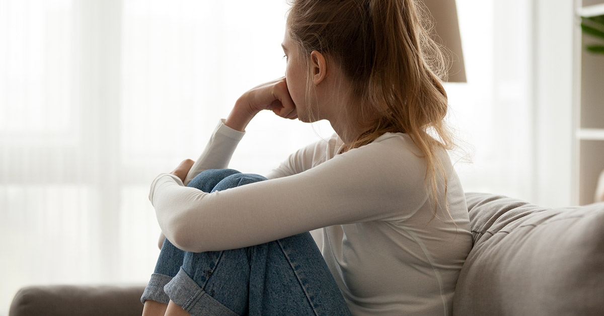 woman sitting on couch in deep thought