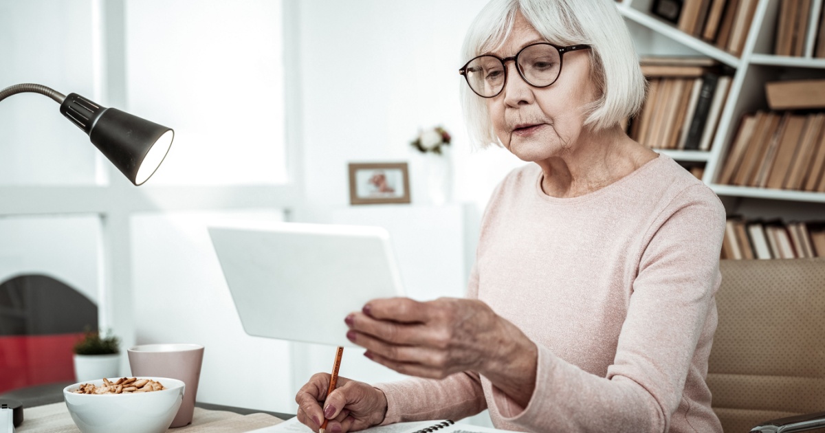 Long-life learning. Pretty female person sitting at her workplace while making notes