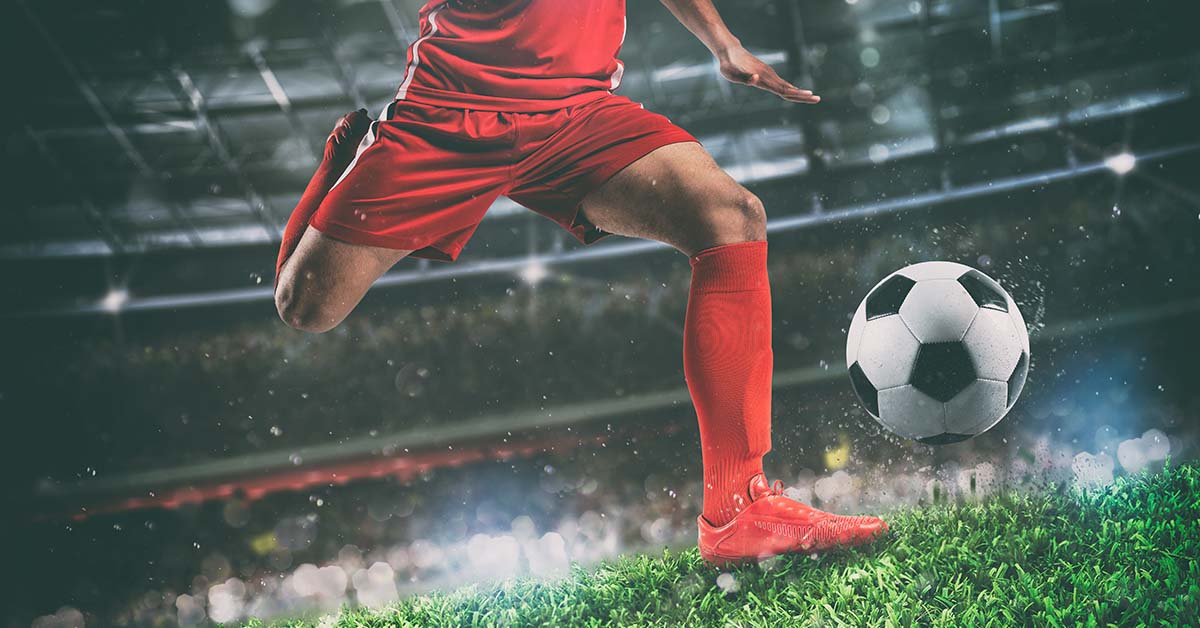 soccer player wearing red about to kick soccer ball