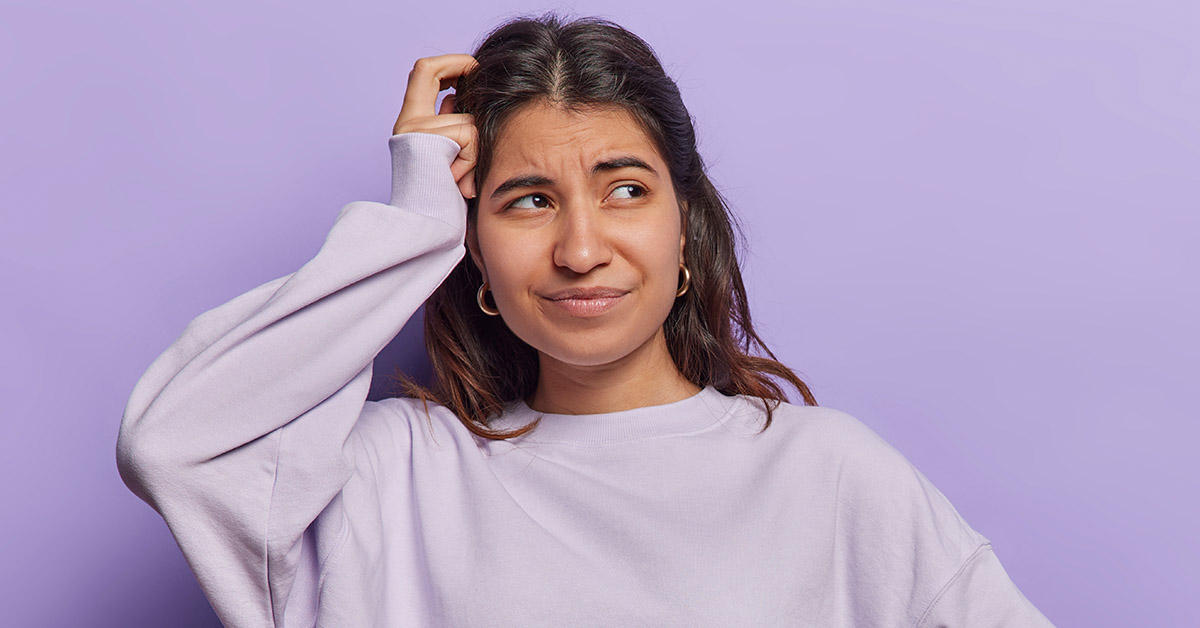 woman puzzled scratching head with purple background