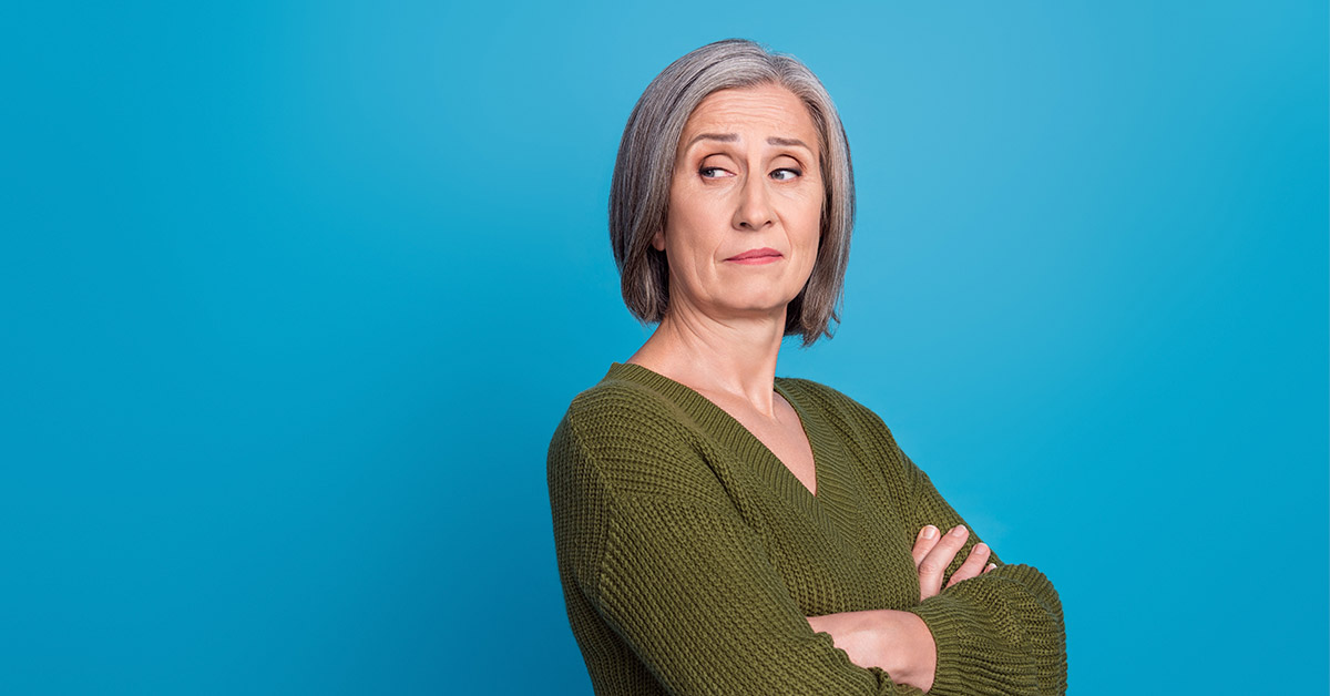 middle aged woman crossing arms looking unamused