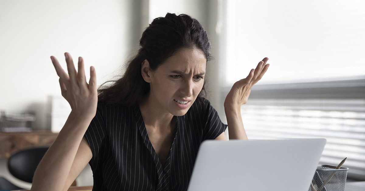 Confused person using a lap top with hands in air in frustration
