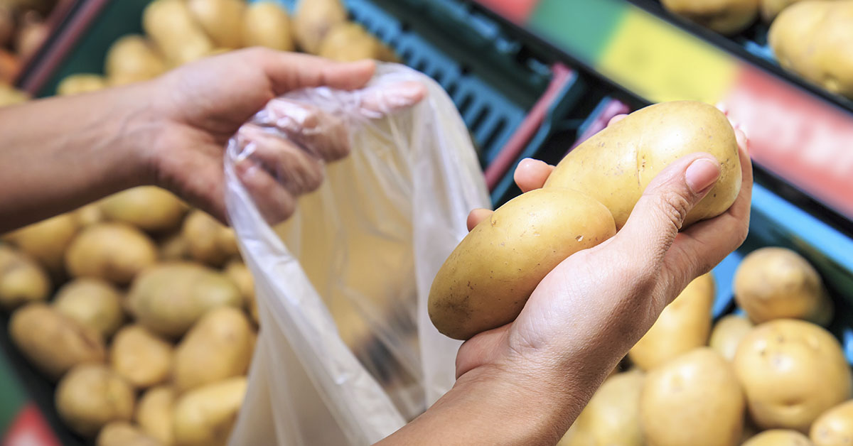 person bagging potatoes at a supermarket