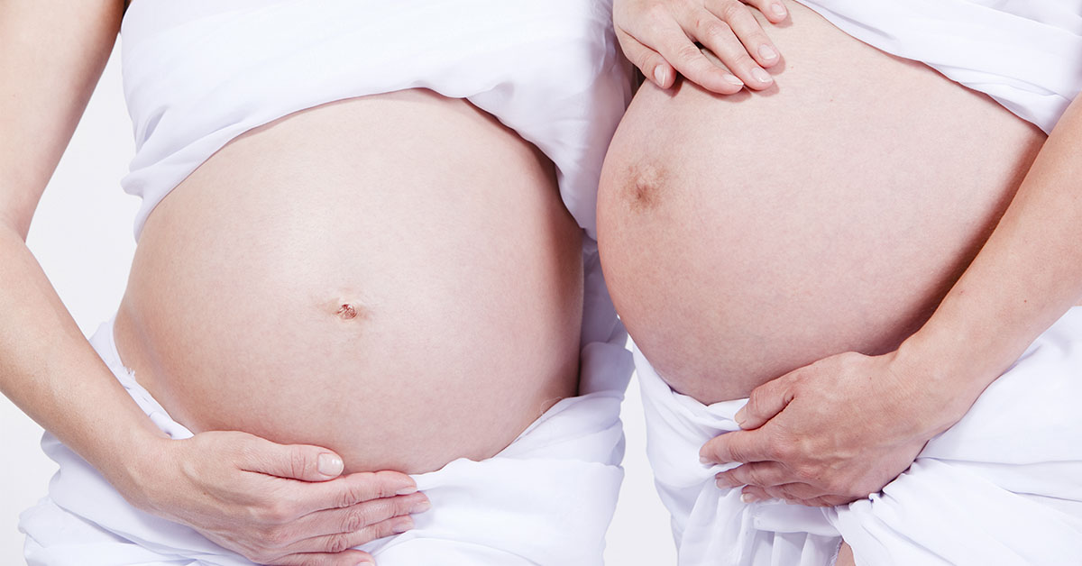 two pregnant women showing their bellies