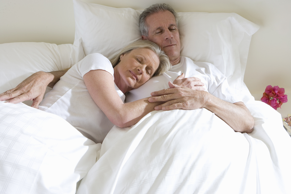 Mature couple sleeping in bed, woman leaning contentedly on manÃ?Â¢Ã¢Â?Â¬Ã¢Â?Â¢s chest