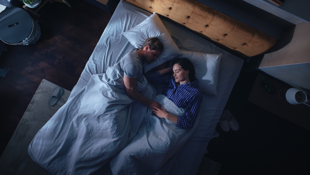 Top View Apartment: Happy Young Couple Sleeping in Bed at Night. Beautiful Girlfriend and Handsome Boyfriend Sleeping Together. Family of two Sweetly Sleeping Facing Each other.