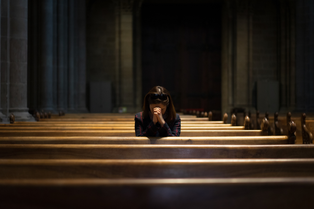 A Christian girl is sitting and praying with humble heart in the church.