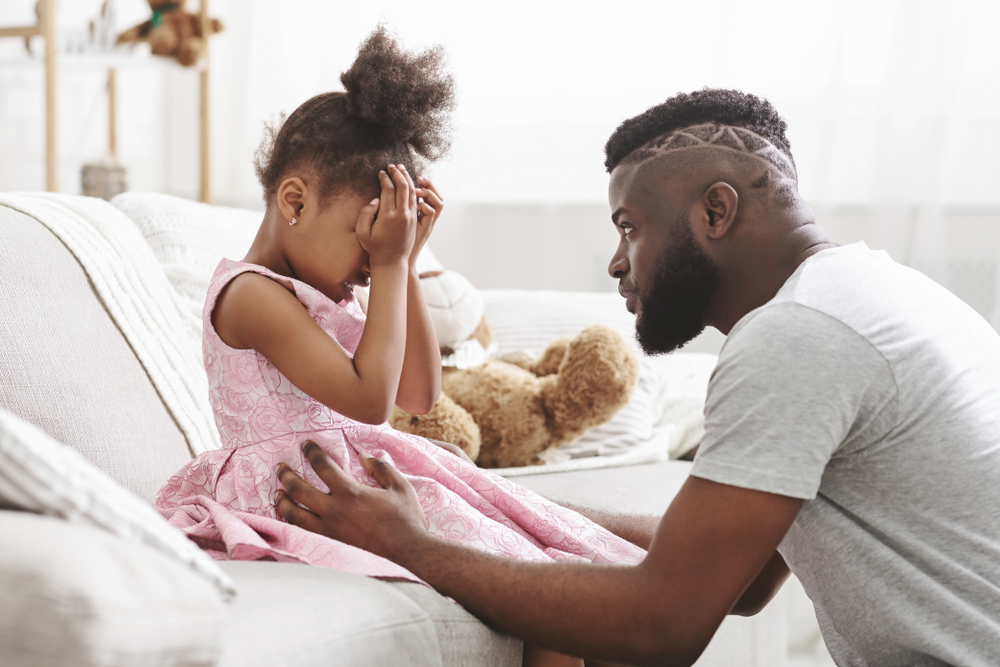 Loving african american dad comforting crying daughter, supporting little stressed girl in tears, giving empathy protection at home
