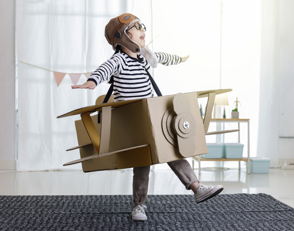 Asian little child girl playing with cardboard toy airplane handicraft isolated in home with copy space for your text, Creative with family and dreaming of flying concept
