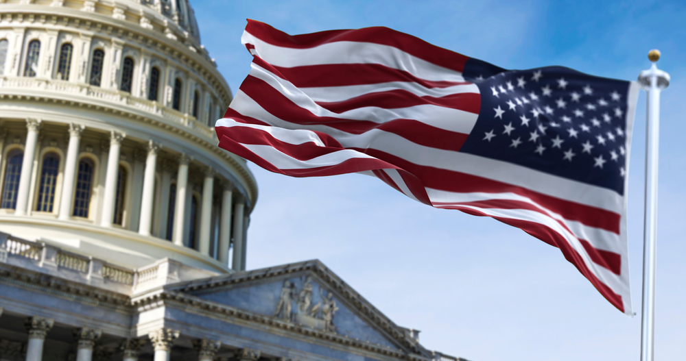 American flag waving with the US Capitol Hill in the background