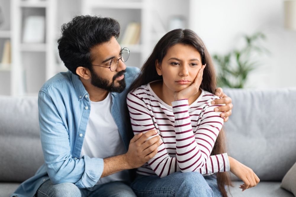 Compassionate eastern husband giving comfort, support to upset wife, holding shoulders, speaking expressing empathy. Man feeling guilty, asking girlfriend to forgive. Relationship, compassion concept