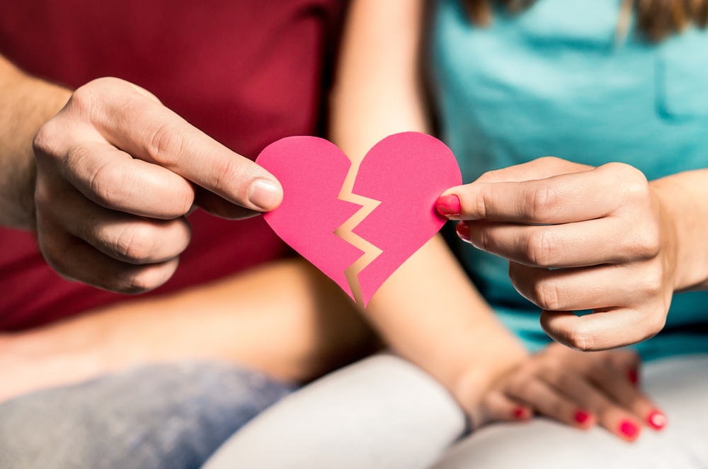 Divorce, breakup or separation. Ripped paper heart in hands of a couple. Finding match and love. Cheating, infidelity, betrayal, or trust problems in relationship. Split up woman and man.